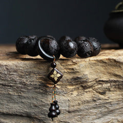 Ebony Wood Yin Yang Gourd Balance Bracelet - side view showing carved relief patterns and ring spacer on rustic wood, carved wood bracelet