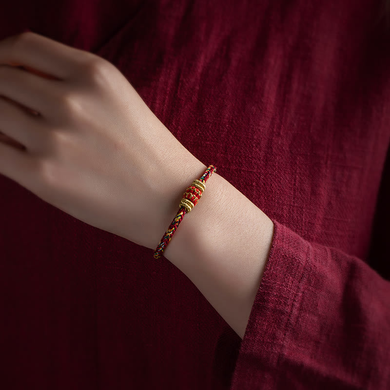 Traditional Chinese lucky red string bracelet with gold knotting detail on woman's wrist, handwoven multicolor cord jewelry for protection and good fortune