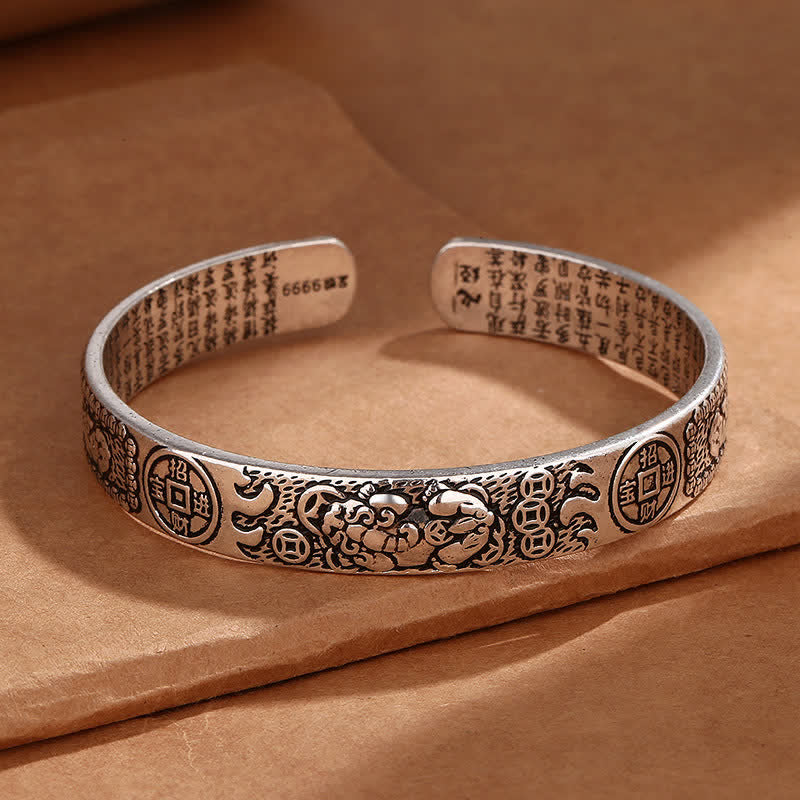 Sterling silver feng shui Pixiu cuff bracelet with lucky coin patterns, engraved Heart Sutra text and oxidized vintage finish on kraft paper
