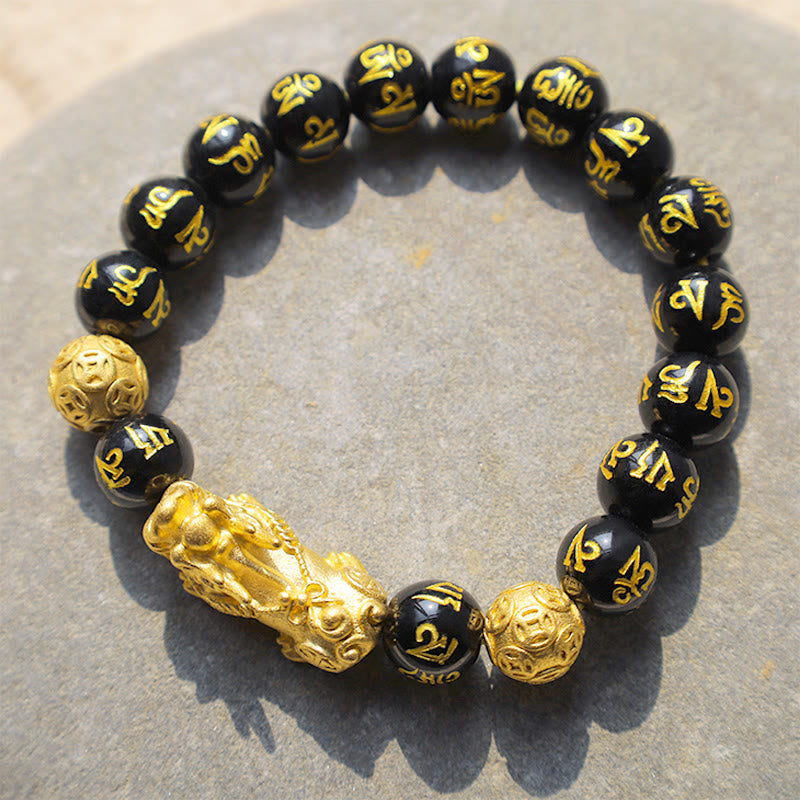 FengShui PiXiu Obsidian Wealth Bracelet - Flat lay on gray stone, six-syllable mantra beads with gold Pixiu, spiritual jewelry