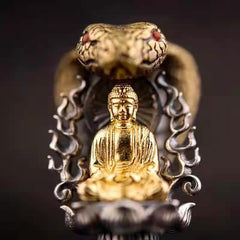 Tibetan Vajra Rotating Pendant – Gold Buddha figure with naga cobra hood and red gemstone eyes on dark silver lotus base, black background shallow depth, frontal
