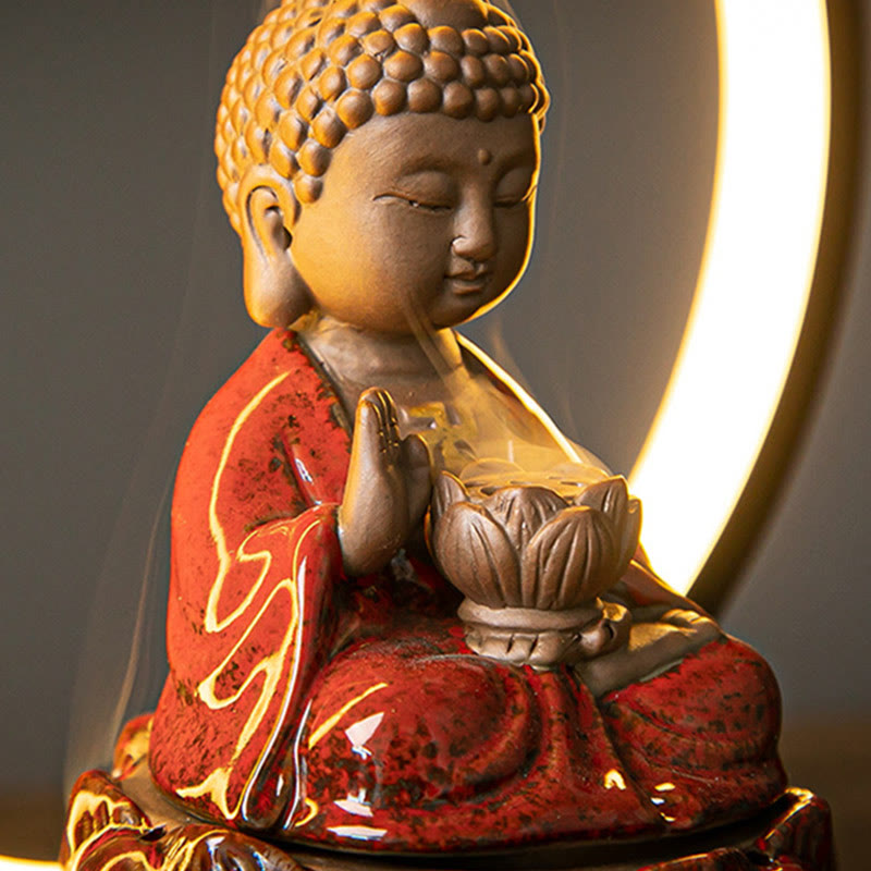 Ceramic Buddha backflow burner three-quarter view with LED halo, crackle red glaze and smoke wisps, zen decor