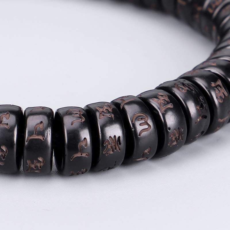 Coconut Shell Om Mani Padme Hum Bracelet – polished black mantra beads with copper inlay close-up, shallow depth macro side angle