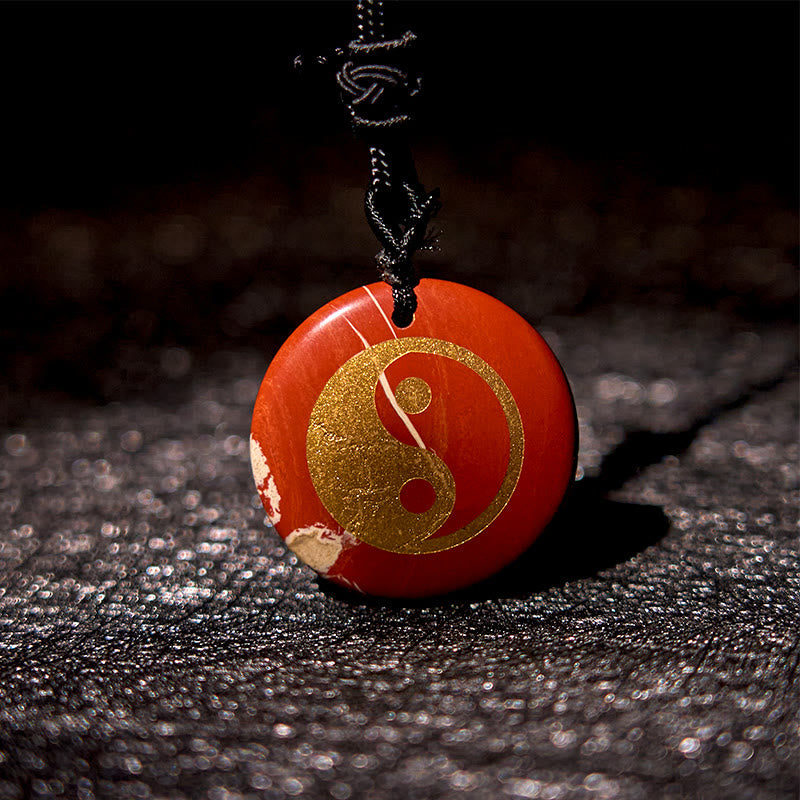 Yin Yang Crystal Necklace – Red stone round pendant with gold yin-yang symbol, natural white veining on black cord, polished 