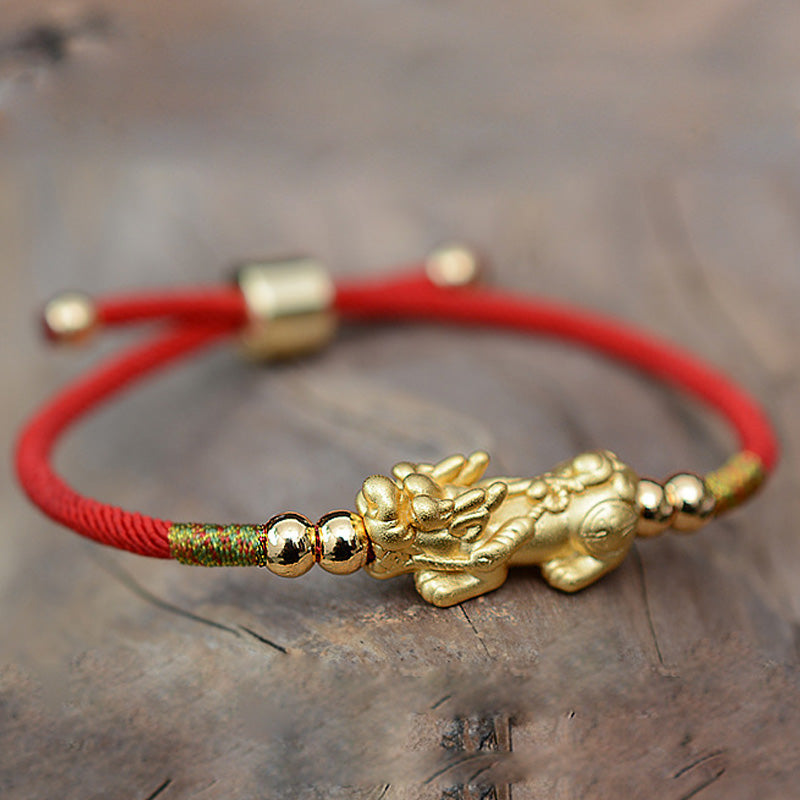Gold-Plated PiXiu Red String Bracelet – gold PiXiu red bracelet alternate angle on stone, prosperity amulet