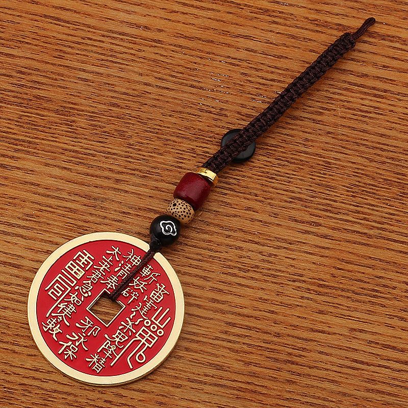 Shan Gui Keychain – red enamel amulet with ancient script on wood grain surface, top-down view