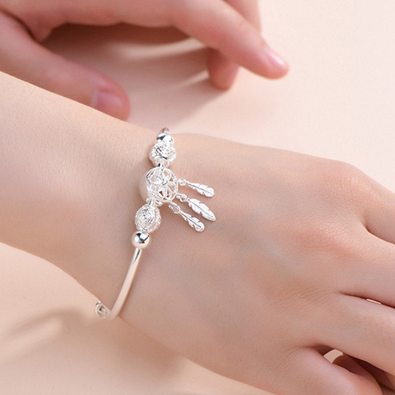 Dream Catcher Blessing Bracelet – Silver cuff on wrist with soft pink bokeh background, worn jewelry shot