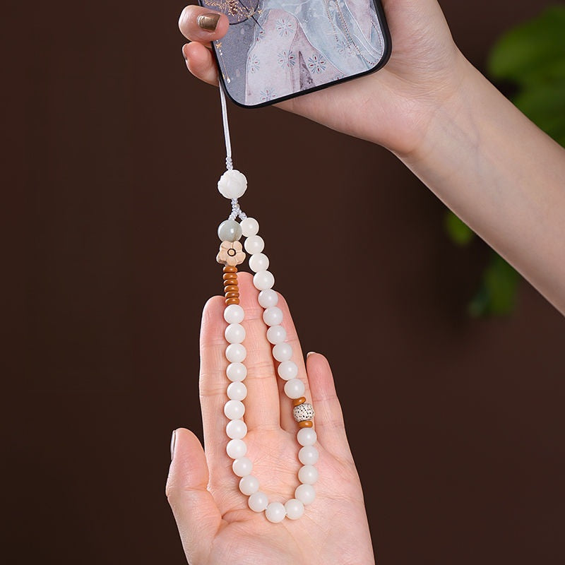 White Jade Bodhi & Jadeite Crystal Phone Charm – Hand holding smartphone showing charm in use, elegant nail art and floral phone case
