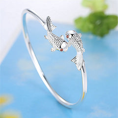 Double Fish Cuff – side view of silver bracelet with two facing koi fish and red eyes