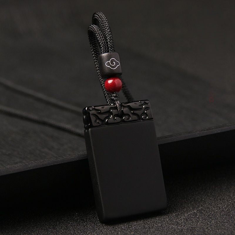 Black Obsidian Pendant – Black obsidian guard plaque with cloud motif on dark slate background, protective talisman