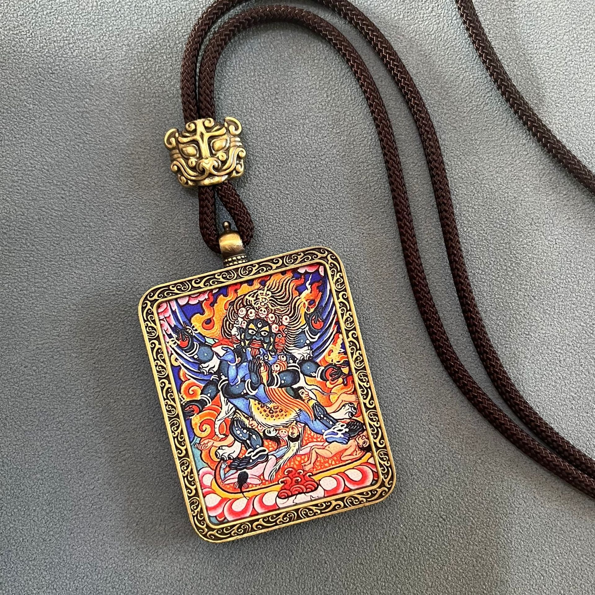 Tibetan Thangka Pendant – blue fierce protector with flaming aureole, gold scroll frame, brown cord, prosperity amulet