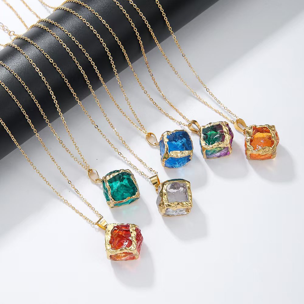 Gemstone Chip Pendant – Six colorful crystal cube necklaces draped on black cylinder, product photography