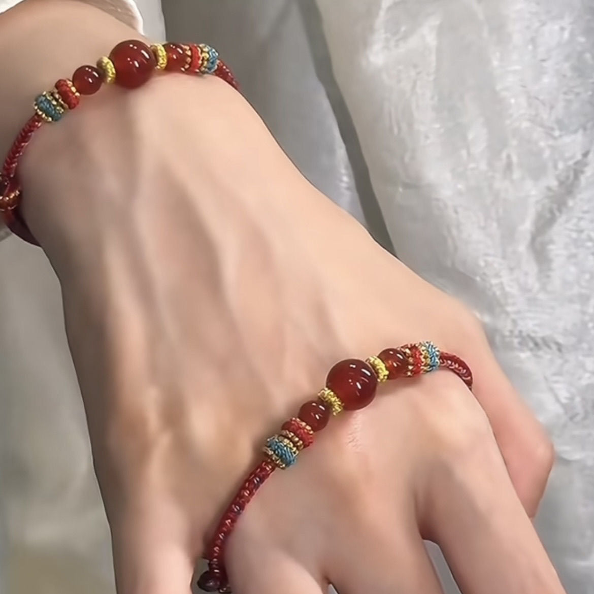 Dunhuang Agate Bracelet – red agate bracelet on wrist over white lace fabric with hand in relaxed pose, everyday spiritual jewelry