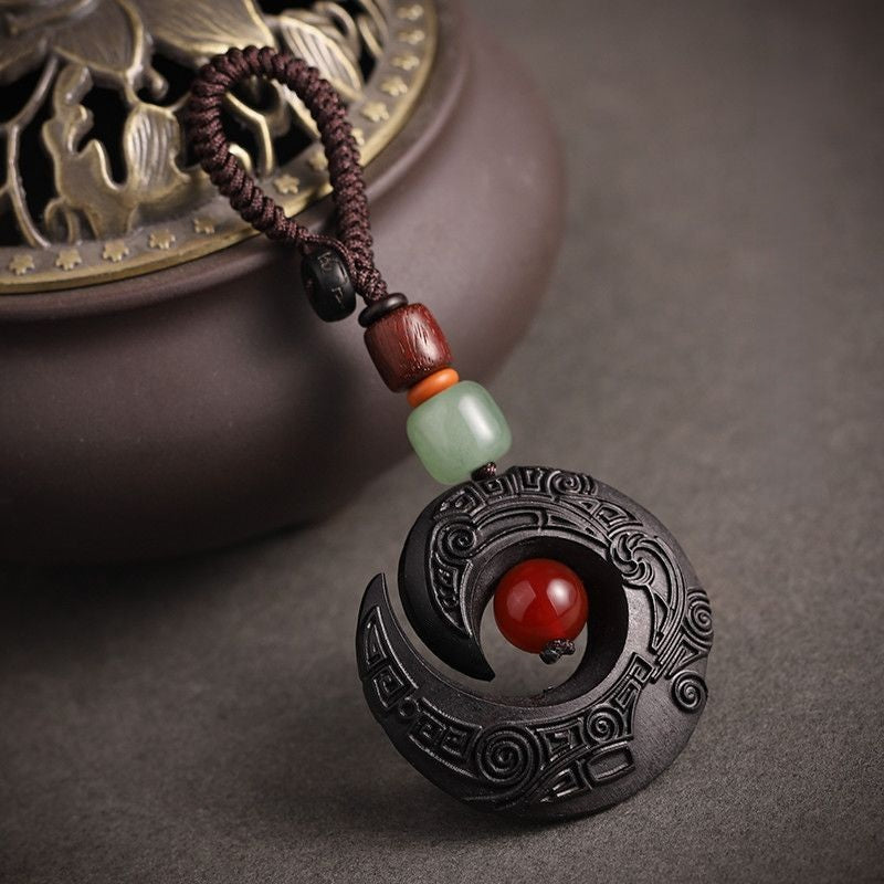 Feng Shui ebony wood protection keychain placed on rolled calligraphy scroll with carved pattern detail