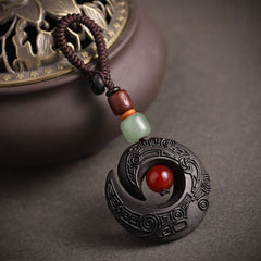 Feng Shui ebony wood protection keychain placed on rolled calligraphy scroll with carved pattern detail