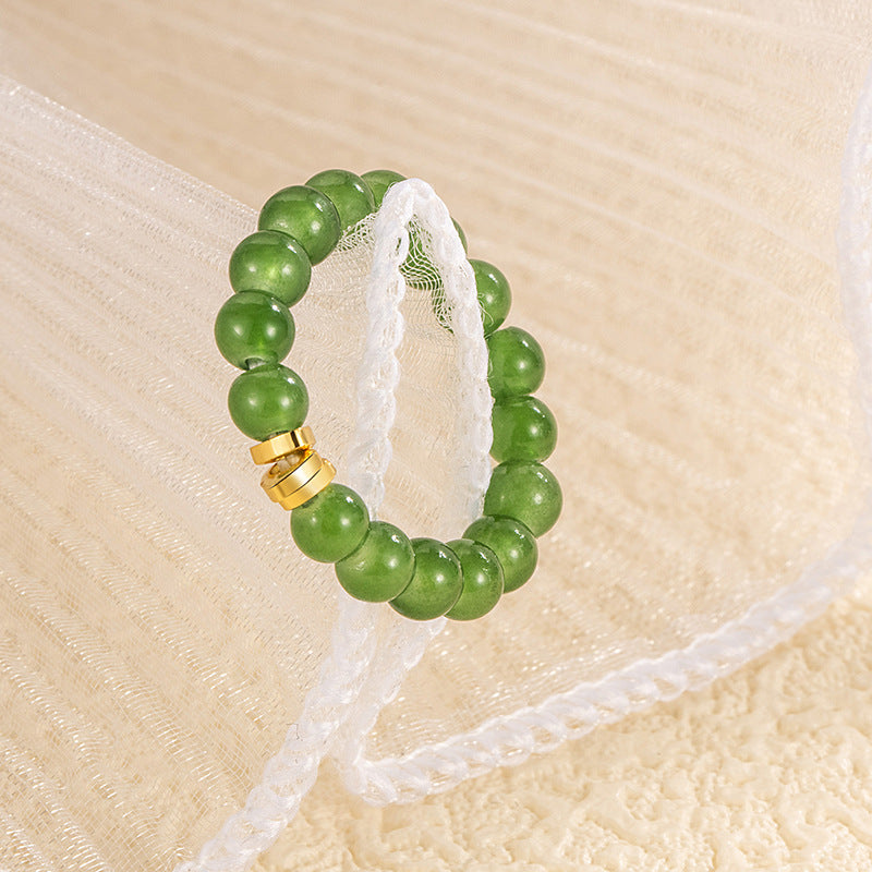 Jade Bead Ring – light green jade ring draped on white lace ribbon, soft beige tulle background, delicate feminine design