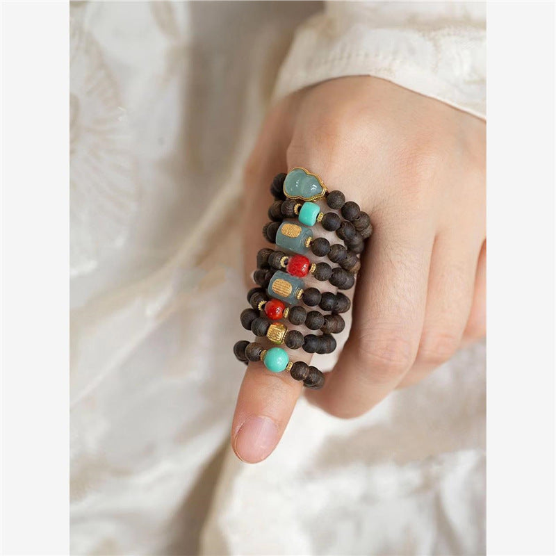 Agarwood Ring – layered rings with jade and gold details against white fabric, minimalist style