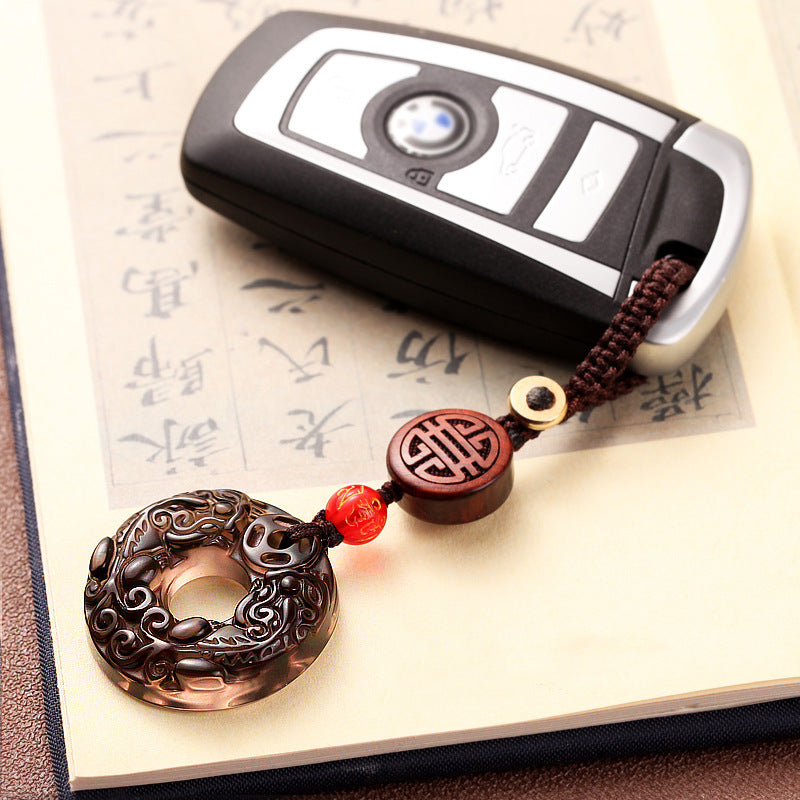 Pixiu Obsidian Keychain – pixiu disc on BMW key over calligraphy paper page, Chinese culture keychain