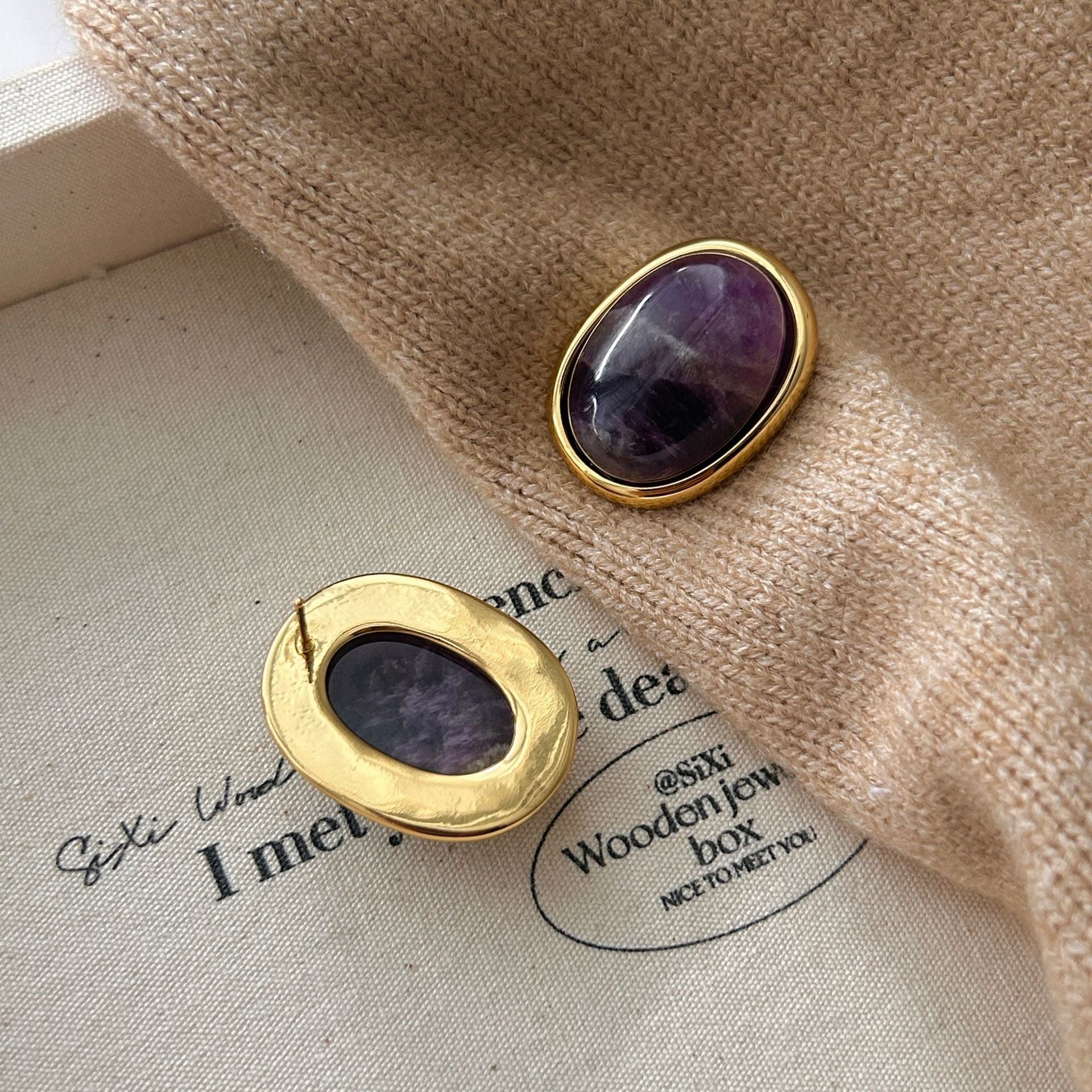 Amethyst Stud Earrings – reverse side of gold bezel amethyst stud showing ear post on cream canvas with brown knit scarf, 925 silver post