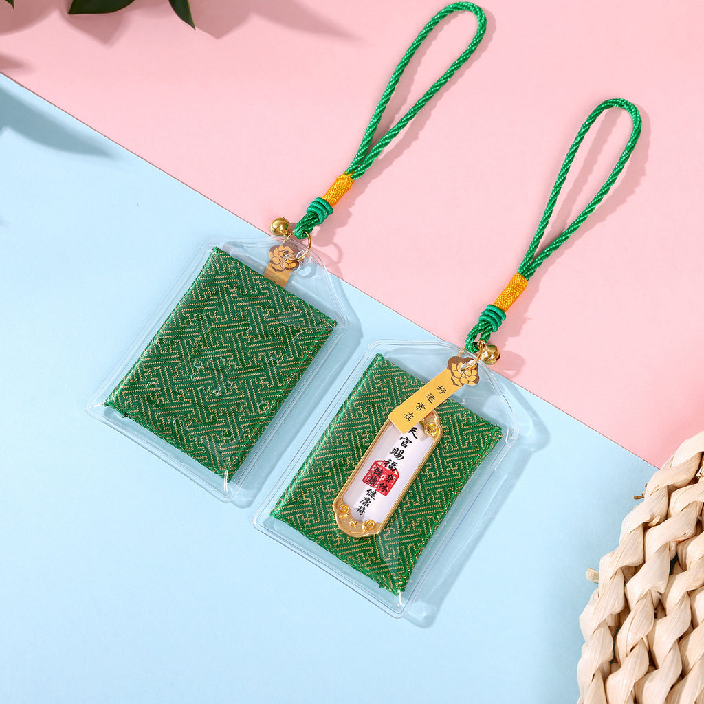 Two green health blessing amulets on pink and blue background