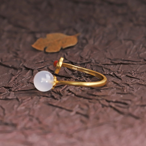 Hetian Jade Clouds Ring – side view white jade bead on gold band with dark textured background and gold leaf, jade ring