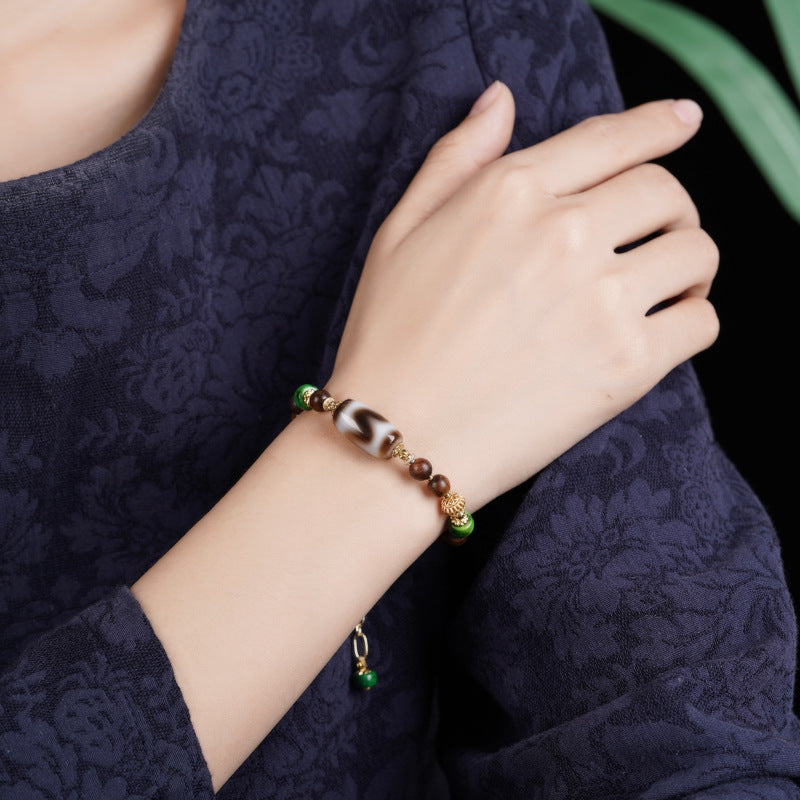 Dzi Rosewood Bracelet – Bracelet worn on wrist with dark blue floral dress, elegant protection jewelry