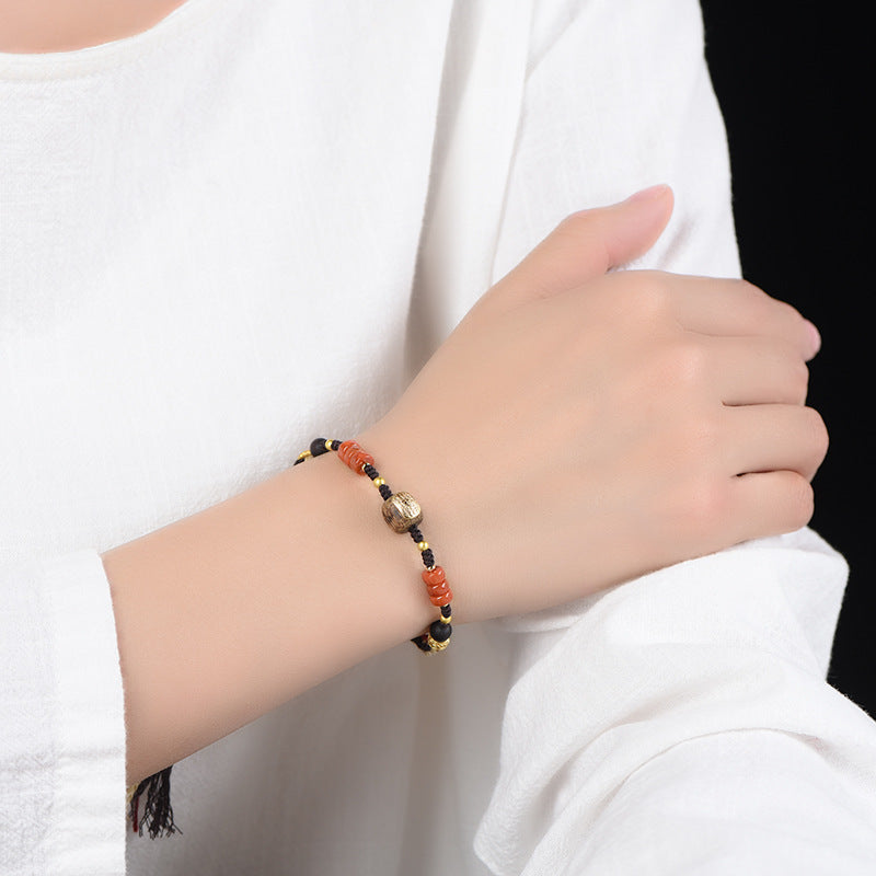 Tibetan Bracelet – on wrist with white sleeve cuff, gold bead center and red accent cords, grounding protection jewelry