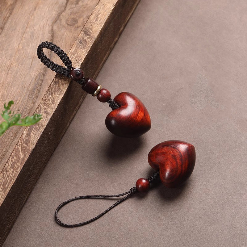 Rosewood Heart Keychain – two hearts on dark surface with green leaf accent, braided and silk cords
