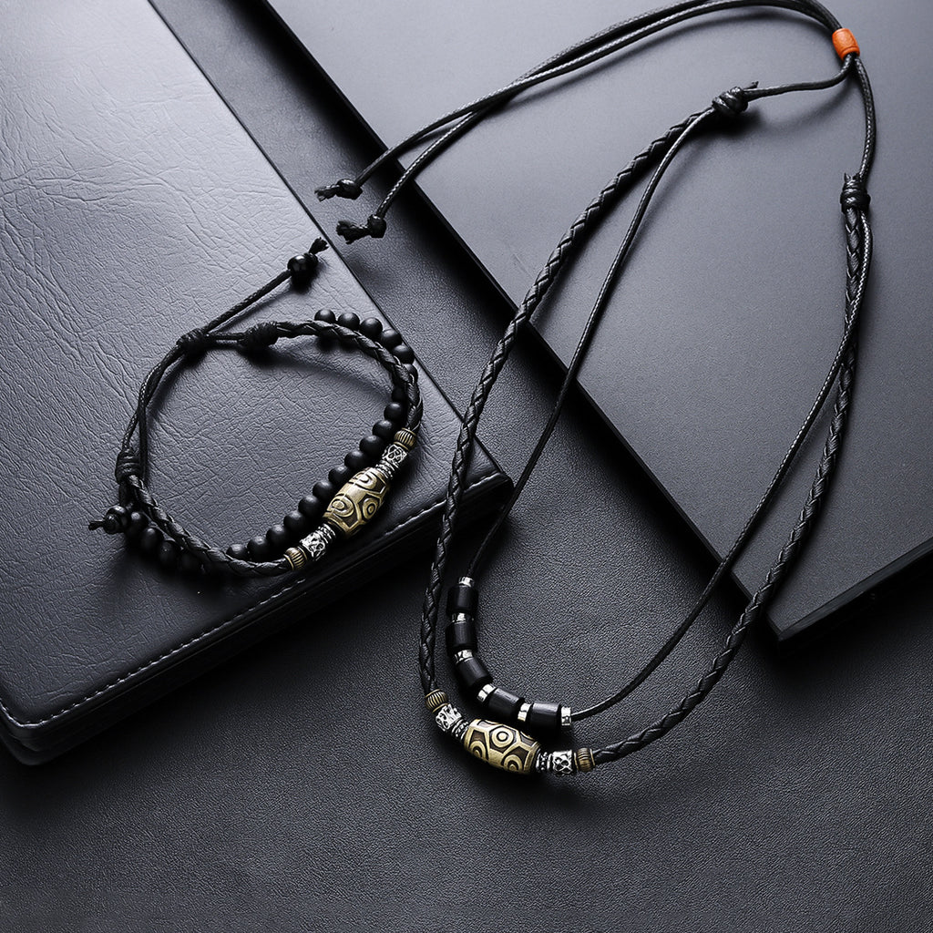 Dzi Bead Set – necklace and bracelet with orange cord detail ends on black leather background, adjustable jewelry