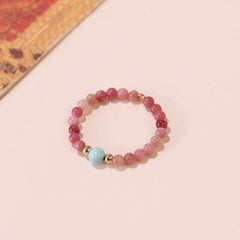 Gemstone Bead Ring – flat lay on blush surface, pink crystal beads with turquoise and gold, warm tones, minimalist gemstone ring