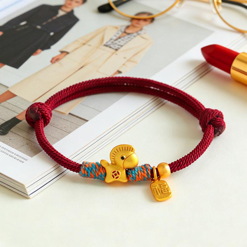 Year of the Horse Bracelet – Red gold horse bracelet on magazine with lipstick, fashion accessory