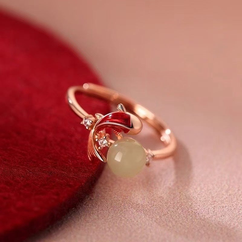 Koi Jade Ring – close-up side view on red velvet, rose gold band with red koi and pale jade, diamond details, luxury jewelry