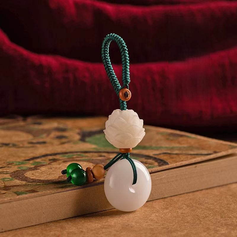 Chalcedony Lotus Keychain – lotus peace buckle resting on antique book with red silk background, Chinese zen gift