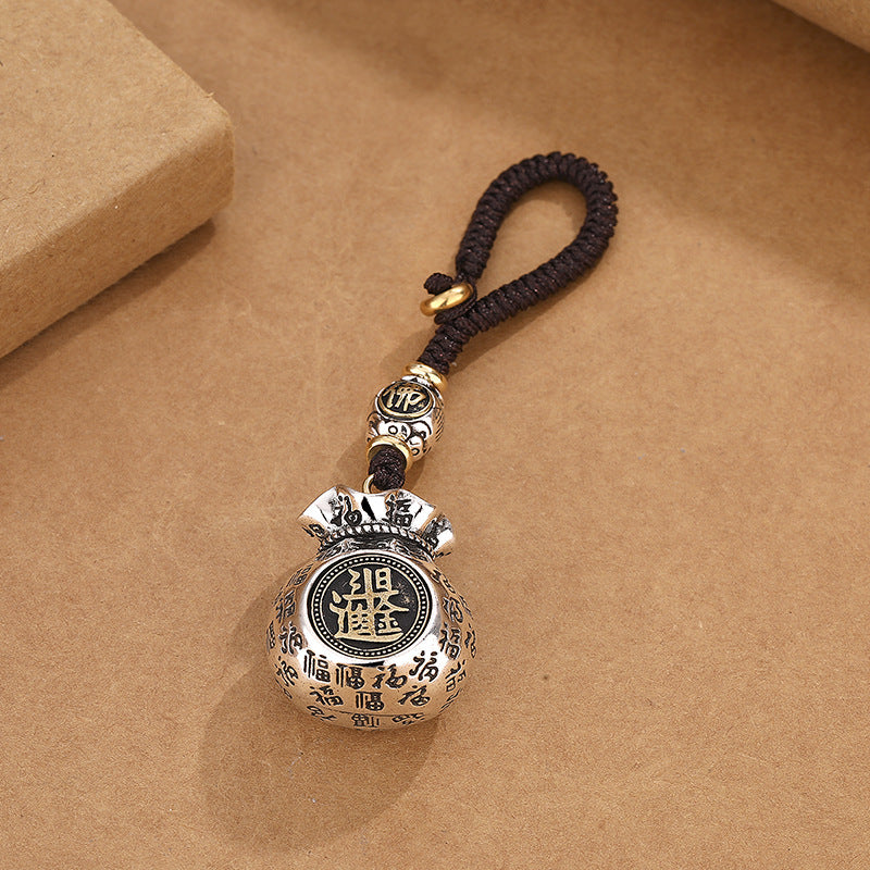 Silver rotating coin money pouch keychain front view with detailed engraving on brown craft background