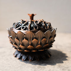 Lotus Incense Burner with pierced lid, three-tiered bronze petals on gray stone, tranquil