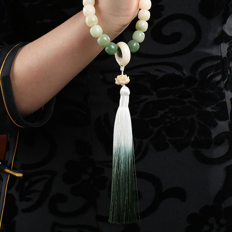 Bodhi Seed Lotus Wisdom Wrist Mala – Prayer bead bracelet worn on hand, black garment with gold trim, ombre green lotus tassel