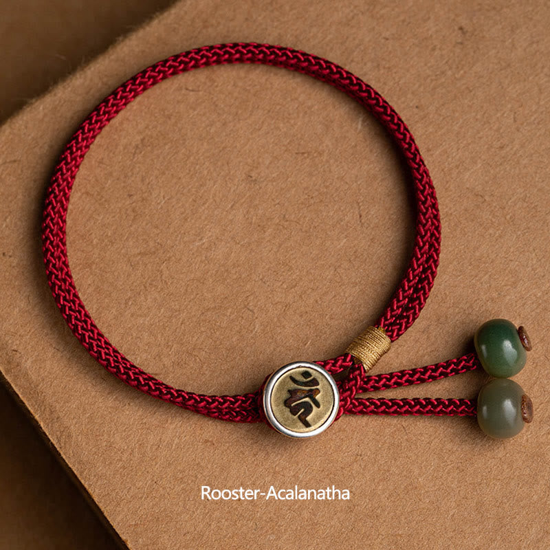 925 Silver Zodiac Natal Buddha Red String Bracelet flat lay, Rooster Acalanatha Bodhisattva Sanskrit seed syllable charm, antique brass medallion with silver rim, forest green and sage jade beads, adjustable red cord