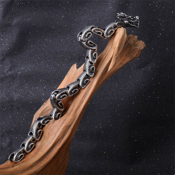 Dragon Titanium Steel Luck Bracelet Bangle - open C-shape on driftwood with starfield background, gothic aesthetic