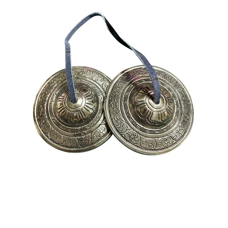 Tibetan Tingsha Bells – Bronze pair with lotus engravings and leather strap on white background, prayer cymbals