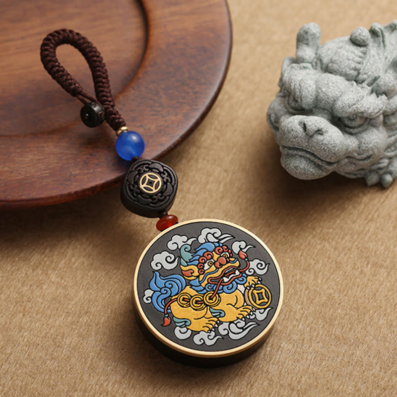 PiXiu Coin Keychain – Painted PiXiu pendant beside stone lion statue on wooden plate