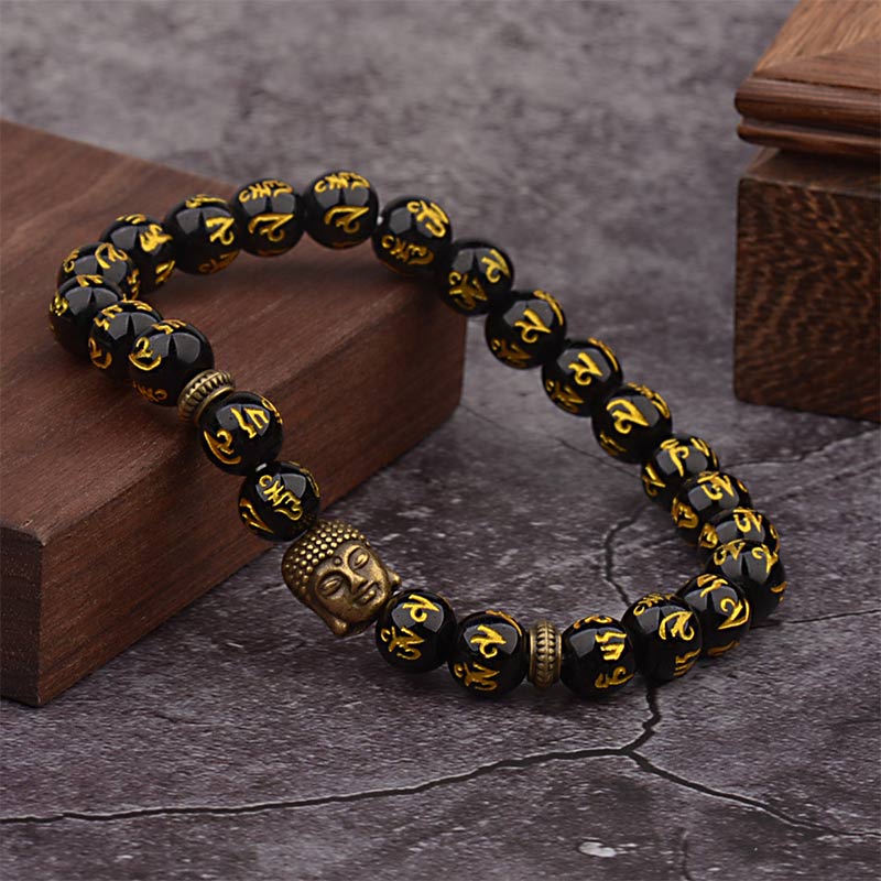 Tibetan Buddha Om Mani Padme Hum Amulet Bracelet - faceted black obsidian beads with gold Tibetan Buddhist mantra, silver Buddha head centerpiece, silver vine-pattern spacer beads, meditation wrist mala on dark surface