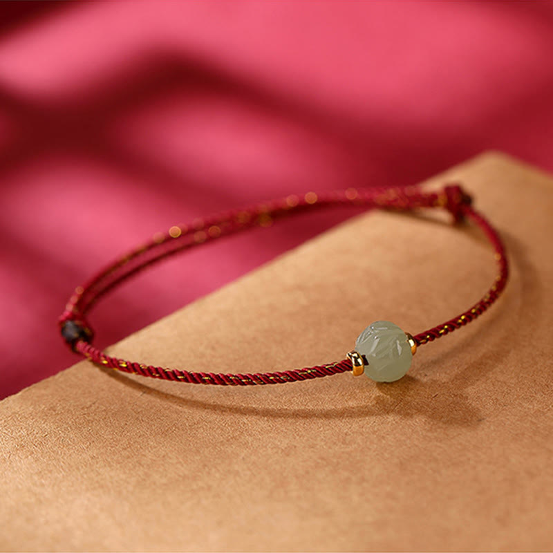 Hetian Jade Lotus Red String Bracelet - Single lotus jade on red cord, low angle shot, pink background, zen