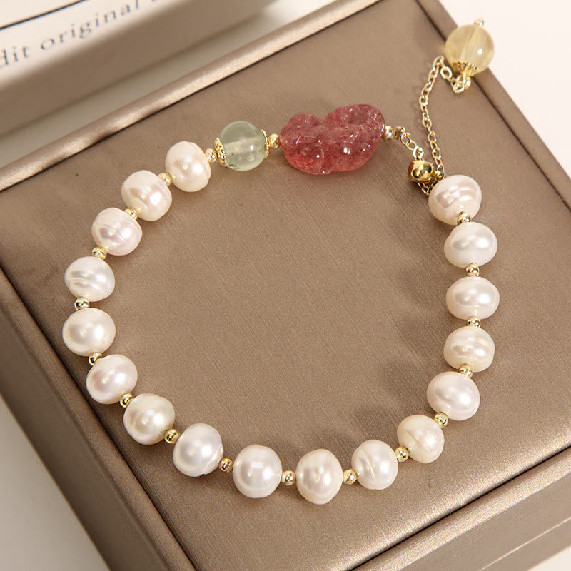 Pearl Strawberry Quartz PiXiu Bracelet – Top view of pearl bracelet with green beads on brown box