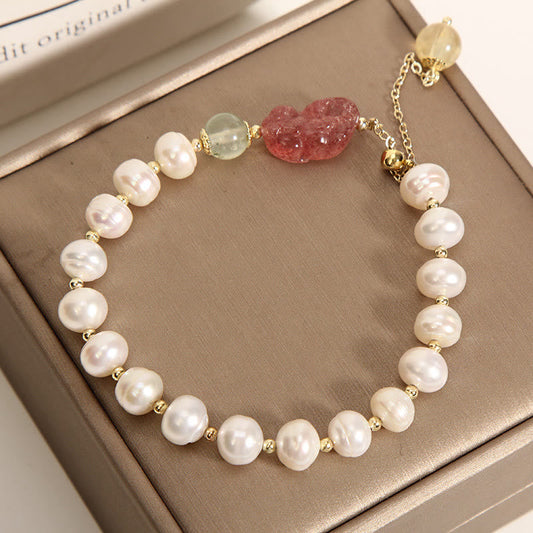 Pearl Strawberry Quartz PiXiu Bracelet – Top view of pearl bracelet with green beads on brown box