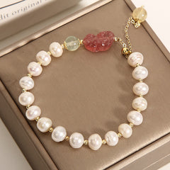 Pearl Strawberry Quartz PiXiu Bracelet – Top view of pearl bracelet with green beads on brown box