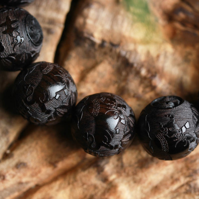 Ebony Wood Yin Yang Gourd Balance Bracelet - macro detail of dragon-carved beads on warm wood grain surface, hand-carved wooden beads