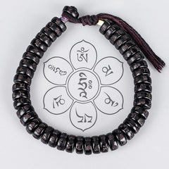 Coconut Shell Om Mani Padme Hum Bracelet – black mantra-inscribed disc beads on maroon cord, lotus mandala watermark, overhead flat lay