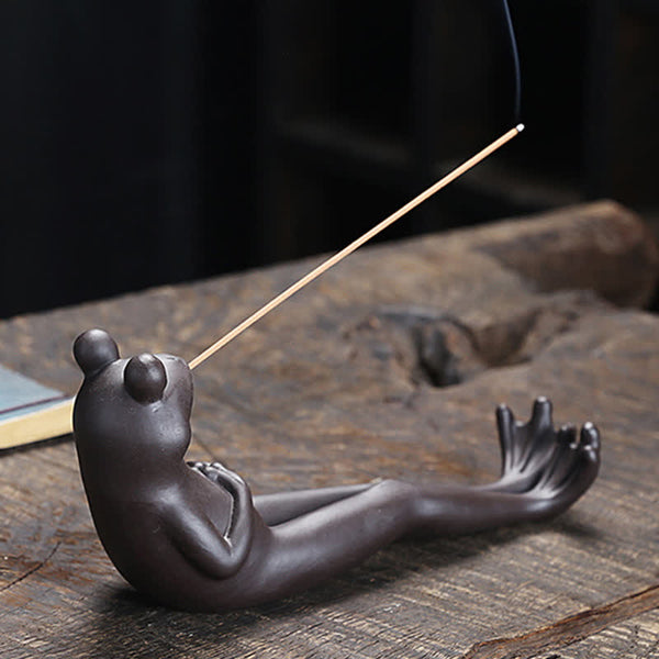 Meditation Frog Ceramic Incense Burner - Chocolate brown frog holding incense stick on wood, peaceful frog decor