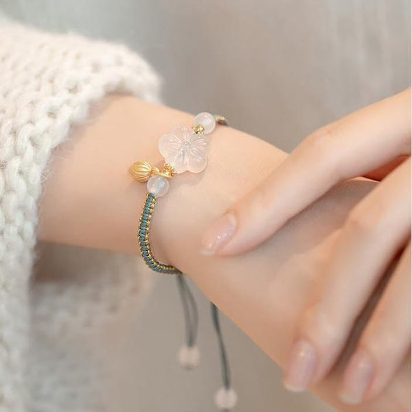 Red Agate Jade Lotus Bracelet – blue-gray cord with mother-of-pearl carved flower and gold leaf charm, white sleeve lifestyle
