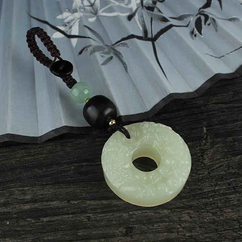 Jade PiXiu Peace Buckle Abundance Key Chain – Jade peace buckle on dark wood with green leaves, nature prosperity